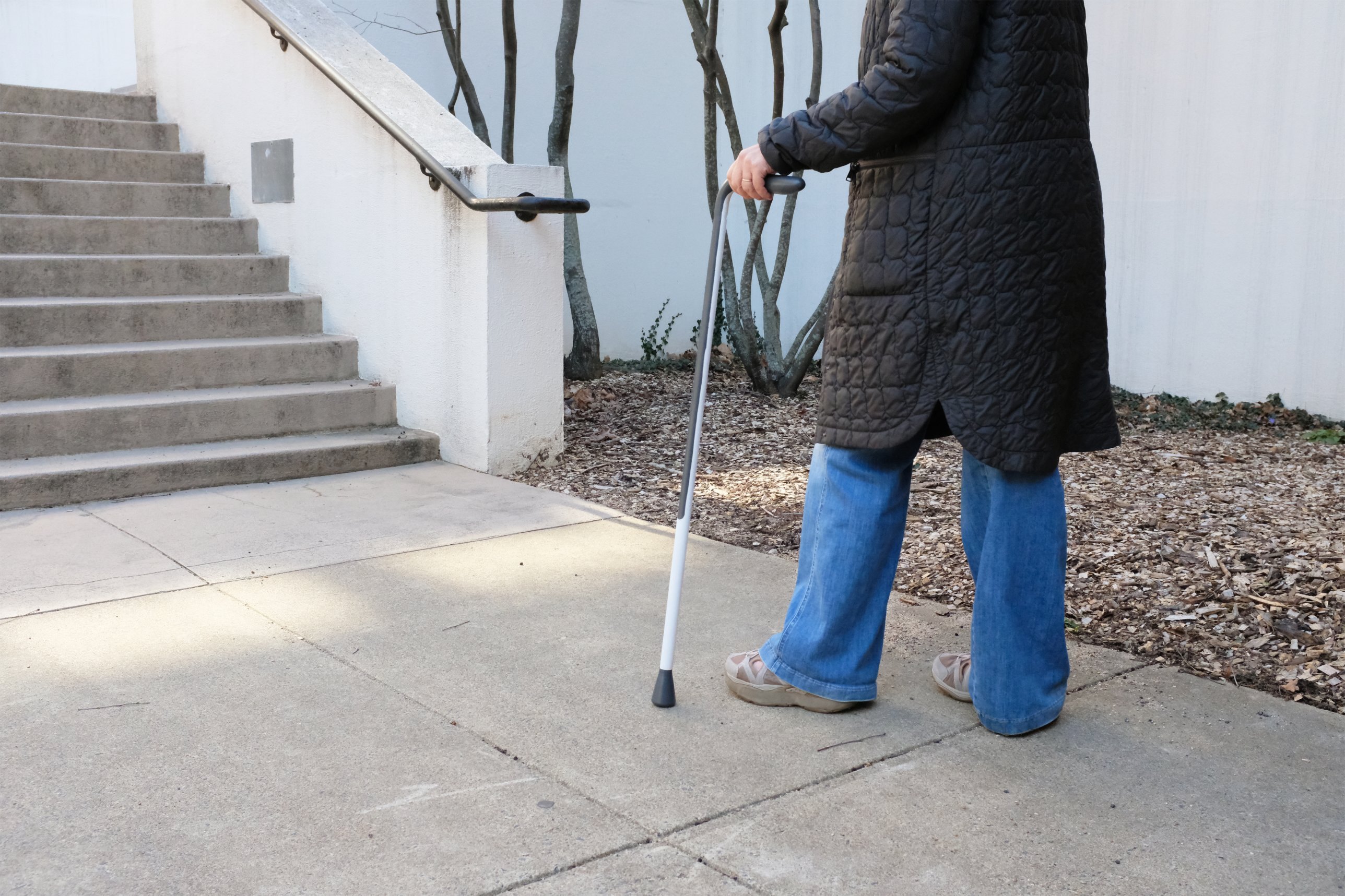 My mom walking with the cane past a set of stairs