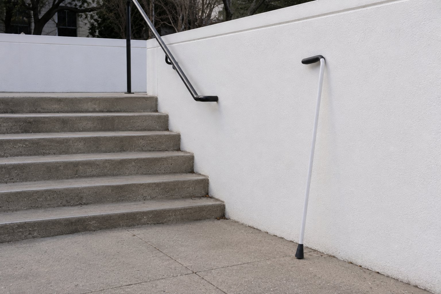 The cane resting on its own against a wall by the stairs